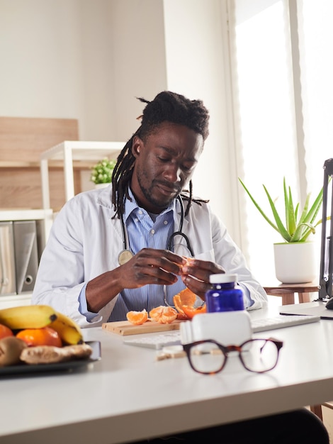 Young nutritionist take a break in office and eat a tangerine