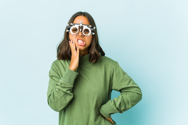 Young oculist latin woman over isolated wall having a strong teeth pain, molar ache.