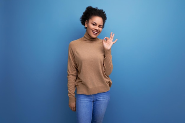 Young optimistic latin woman with curly hair smiling on background with copy space