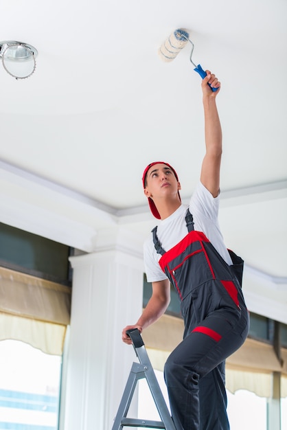 Young painter painting the ceiling in construction concept