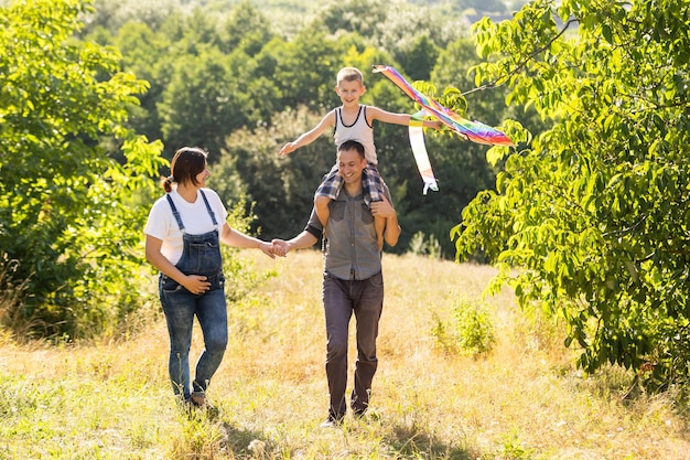 Young parents go with the son on the wheat field . The little son is happy when he is played.