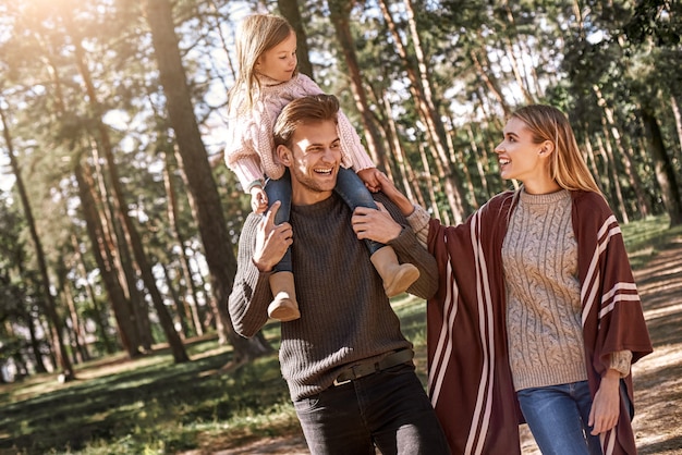 Young parents with little daughter in autumn forest closeup