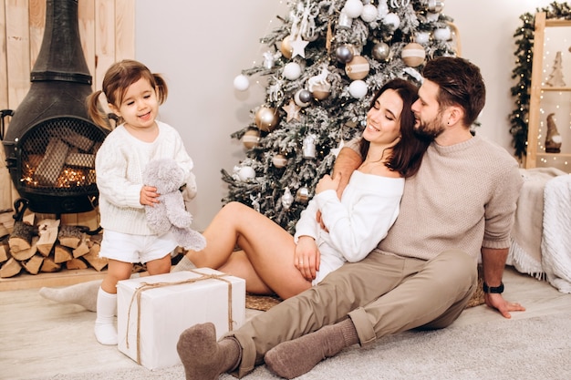 Young parents with a small daughter near the Christmas tree