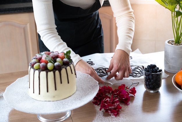 Photo young pastry chef cooking a delicious homemade chocolate cake with fruits in the kitchen