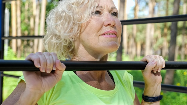 Young pensioner does pullups on horizontal bar closeup