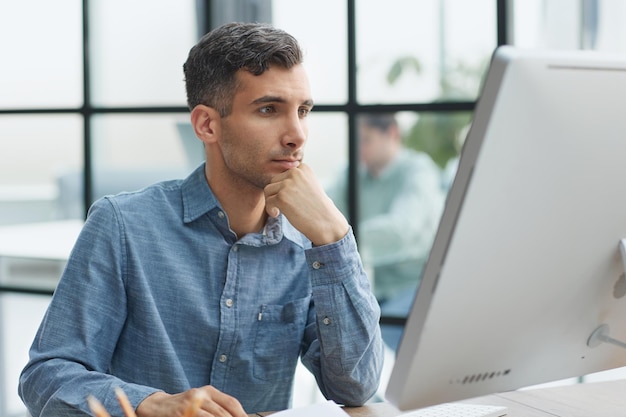 A young pensive man works in the office and thinks about something