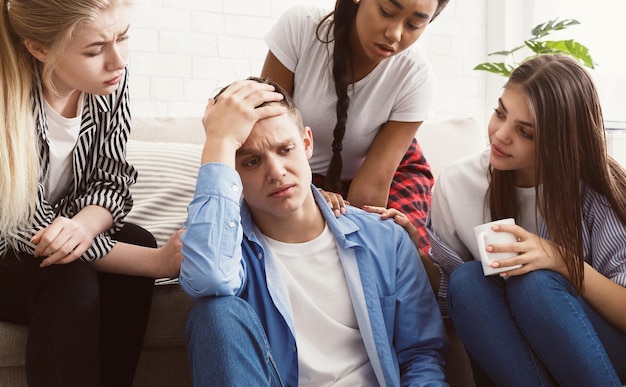 Young people comforting their upset friend at home