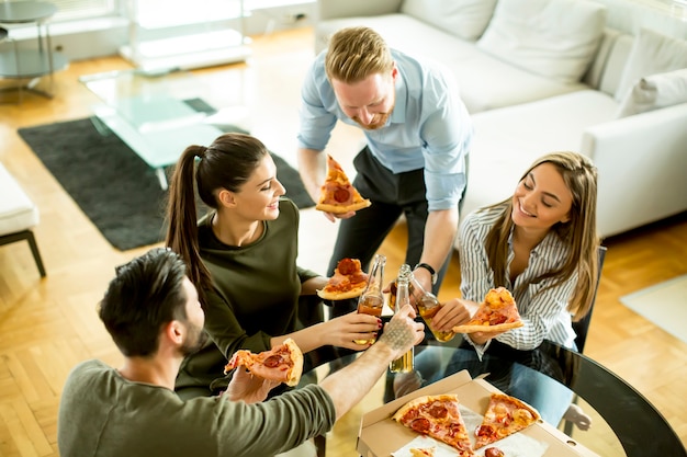 Young people eating pizza and drinking cider in the room