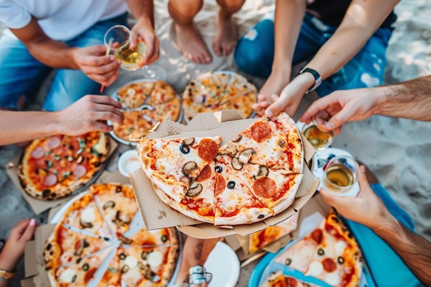 Young people eating pizza and smoking shisha at the beach