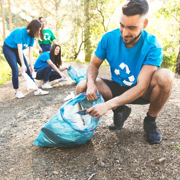 Young people picking garbage in woods