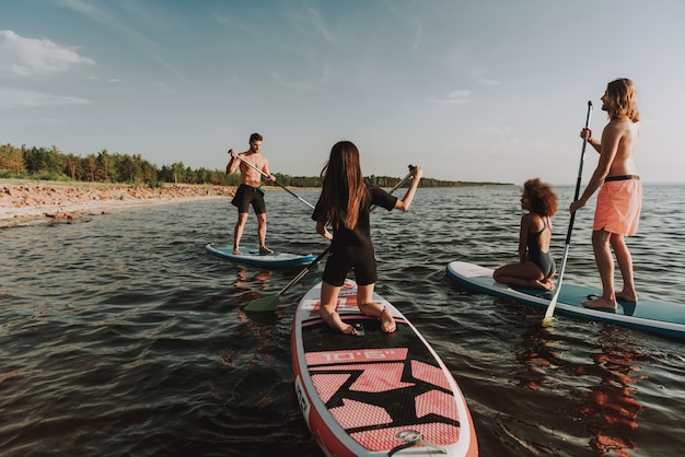 Young People Rowing Surfs In Sea With Paddles.