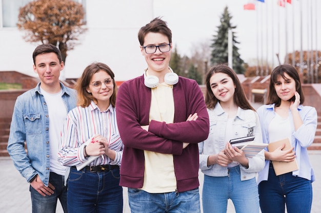 Young people standing with books looking at camera