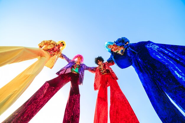 Young people on stilts posing against the blue sky.