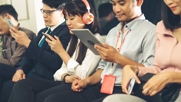 Young people using mobile phones and tablets in public underground train