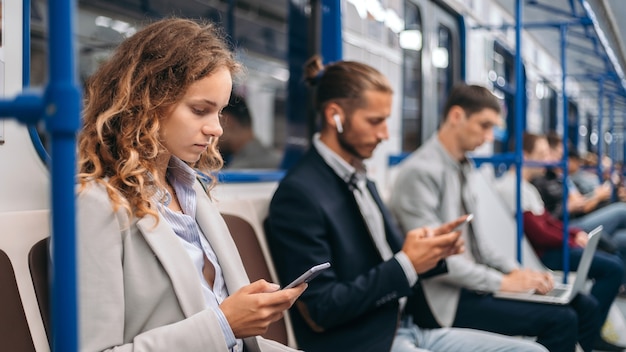 Young people using their devices while sitting in a subway car 