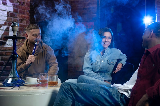 Young people vaping from a hookah in a bar