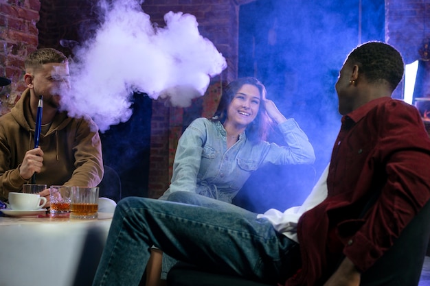 Young people vaping from a hookah in a bar