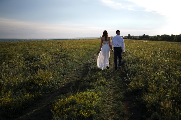 young people walk in an embrace across the field. couple in love