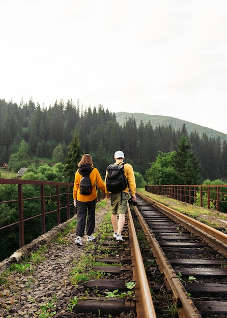 young people walking holding hands on the railway track on a viaduct in the mountains