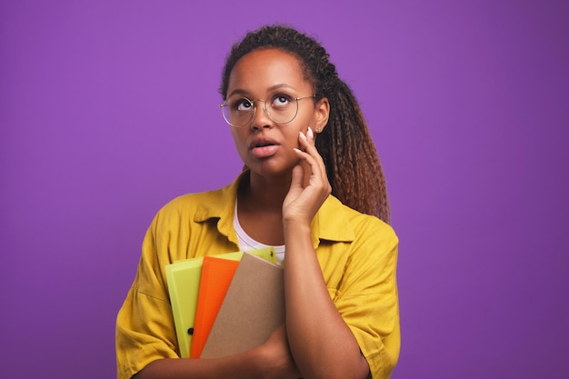 Young perplexed african american woman freelancer holds folders with documents