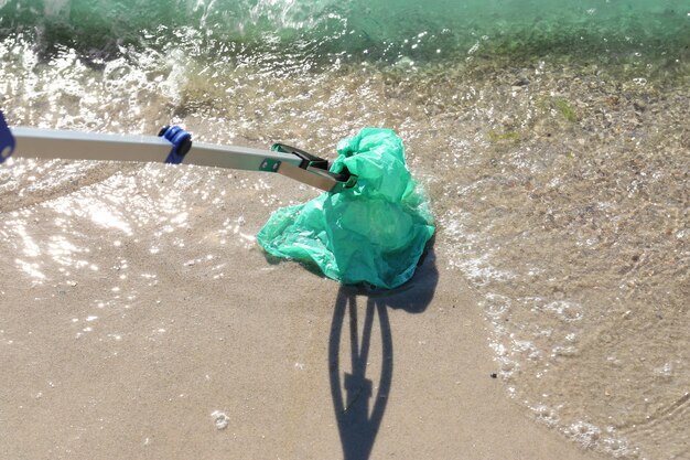 Photo young person cleaning beach area with trash picker volunteer concept