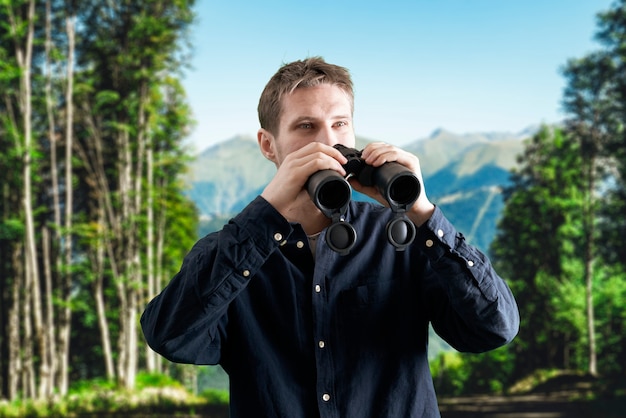 A young person hiking in the mountains and using binoculars, travel concept