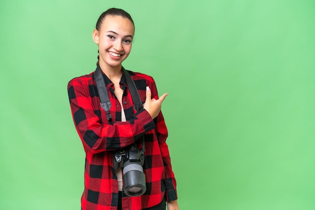 Young photographer Arab woman over isolated background pointing back