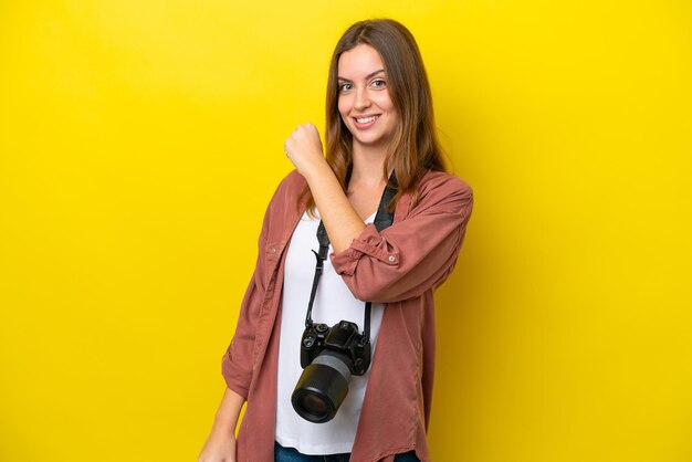 Young photographer caucasian woman isolated on yellow background celebrating a victory