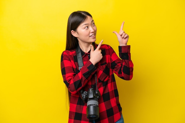 Young photographer Chinese woman isolated on yellow background pointing with the index finger a great idea