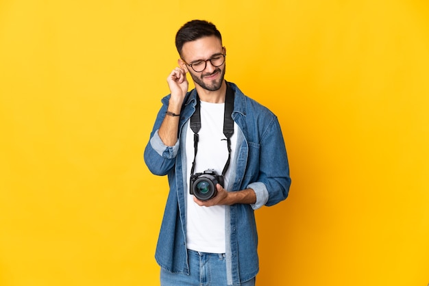 Young photographer girl isolated on yellow background frustrated and covering ears