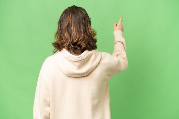 Young photographer man over isolated background pointing back with the index finger