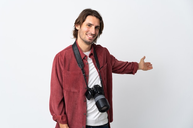 Young photographer man isolated on white wall extending hands to the side for inviting to come