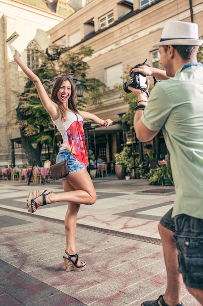 Young photographer taking photo of his very happy girlfriend