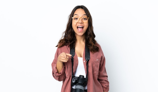 Young photographer woman over isolated white background surprised and pointing front