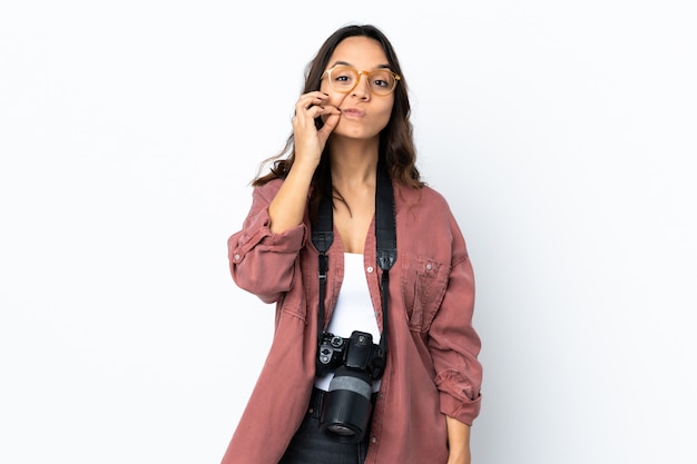 Young photographer woman over isolated white wall showing a sign of silence gesture