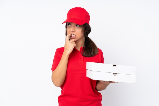 Young Pizza delivery girl over isolated white wall nervous and scared