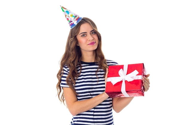 Young pleasant woman in stripped Tshirt and celebration cap with long hair showing red present