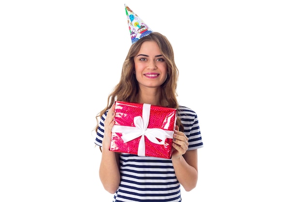 Young pleasant woman in stripped Tshirt and celebration cap with long hair showing red present