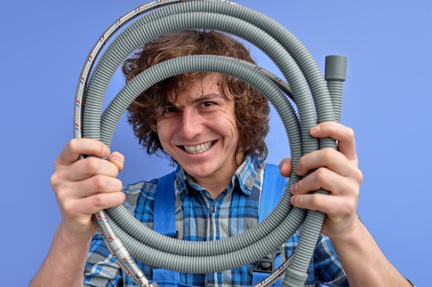 Photo young plumber holding hose from sink in hands