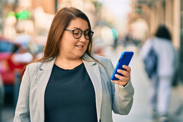 Young plus size businesswoman smiling happy using smartphone at the city