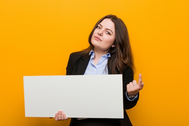 Young plus size curvy woman holding a placard pointing with finger at you as if inviting come closer.