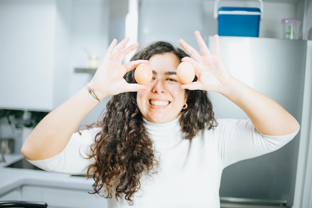 Young plus size spanish woman blogging about his diet and eating habits at a modern kitchen taking pictures and cooking. Sitting on a modern stool and having fun. Losing wight concept