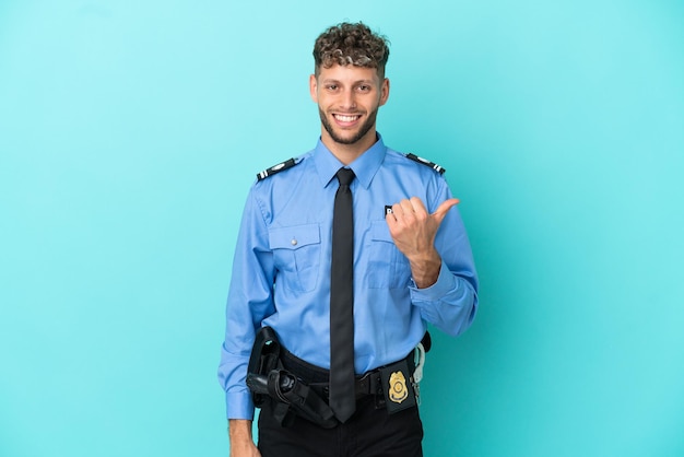 Young police blonde man isolated white on blue background pointing to the side to present a product