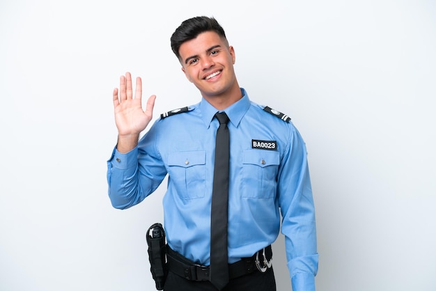 Young police caucasian man isolated on white background saluting with hand with happy expression