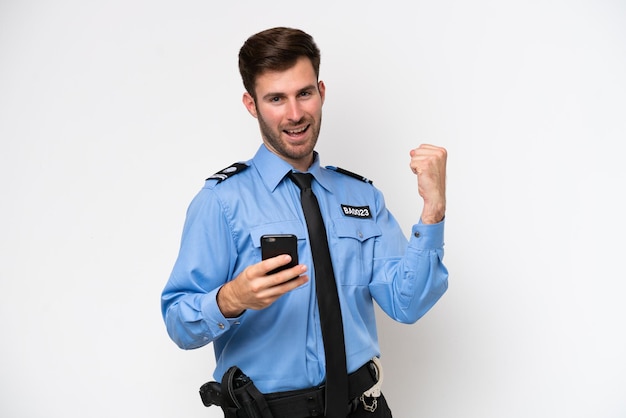 Young police caucasian man isolated on white background with phone in victory position