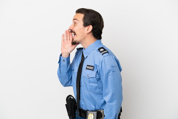 Young police man over isolated background white shouting with mouth wide open to the lateral