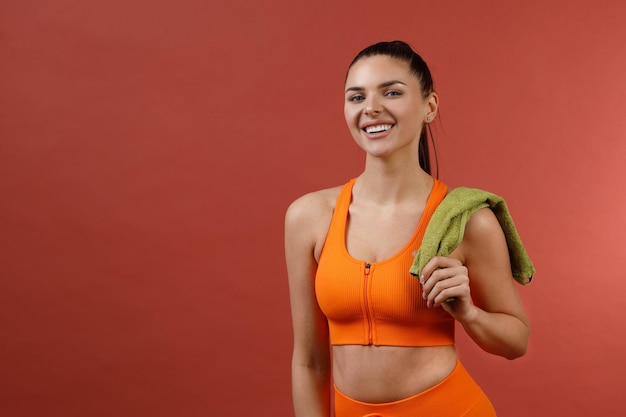 Young positive smiling woman in orange fitness sport outfit cloth studio isolated shot