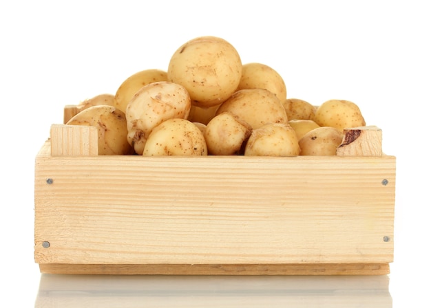 Young potatoes in a wooden box isolated on white close-up