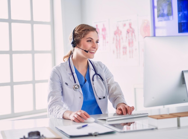 Young practitioner doctor working at the clinic reception desk she is answering phone calls and sche