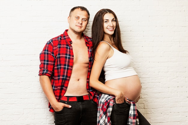 Young pregnant couple hugging and smiling. Waiting for birth and tender relationship.